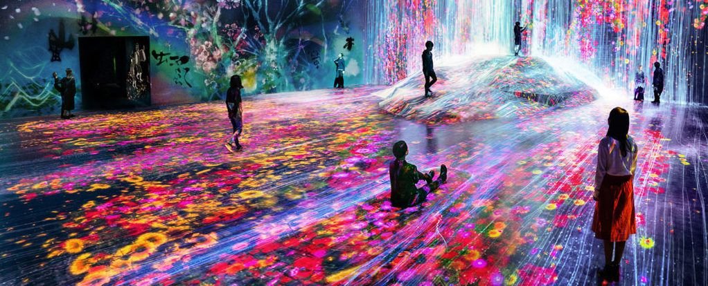 varios niños disfrutando de una proyección inmersiva que simula una cascada de flores