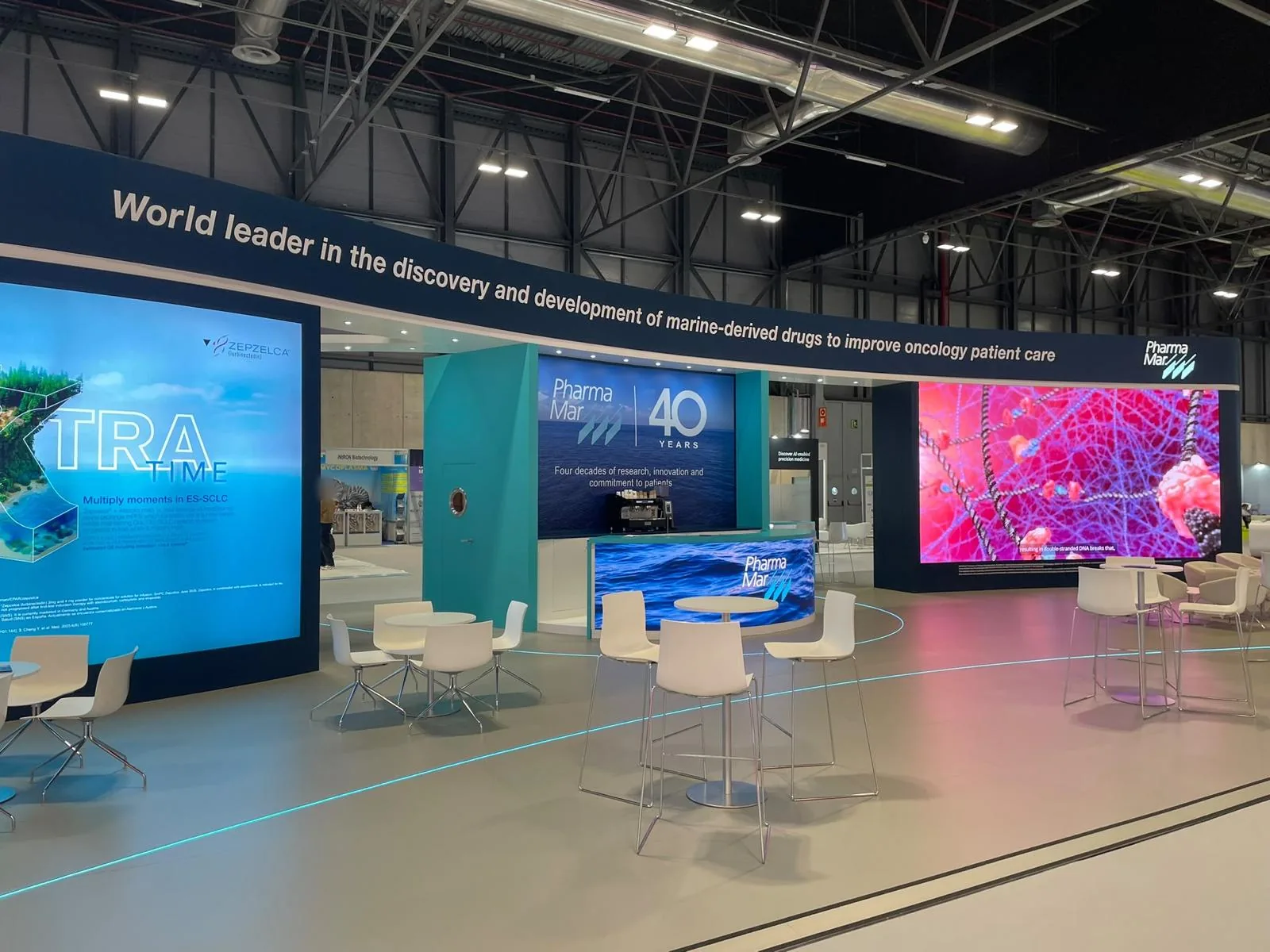 Stand de PharmaMar en ESMO 2026 con mostrador LED curvo y dos pantallas LED de gran formato en IFEMA Madrid