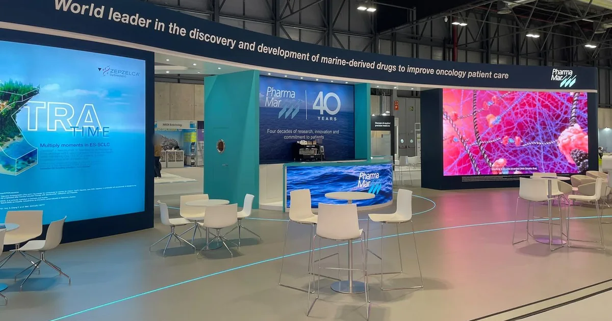 Stand de PharmaMar en el Congreso ESMO 2026 en IFEMA Madrid con mostrador LED curvo y dos pantallas LED de gran formato